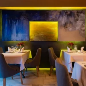 Salón comedor con decoración abstracta geometrica, mesas con manteles blancos elegantes y decoración floral del restaurante italiano San Marco Santa Cruz